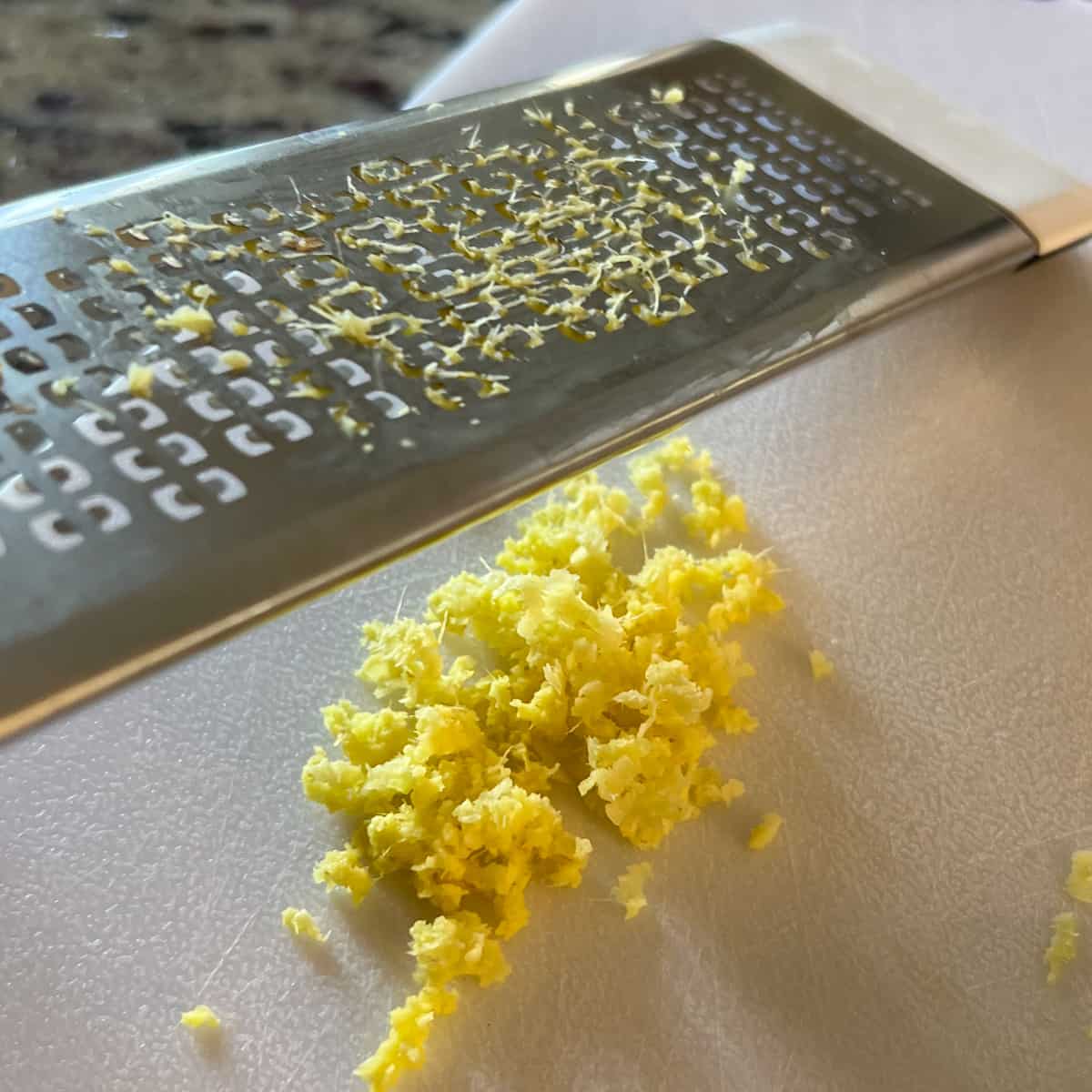 side view of fresh ginger being grated with a microplane grater