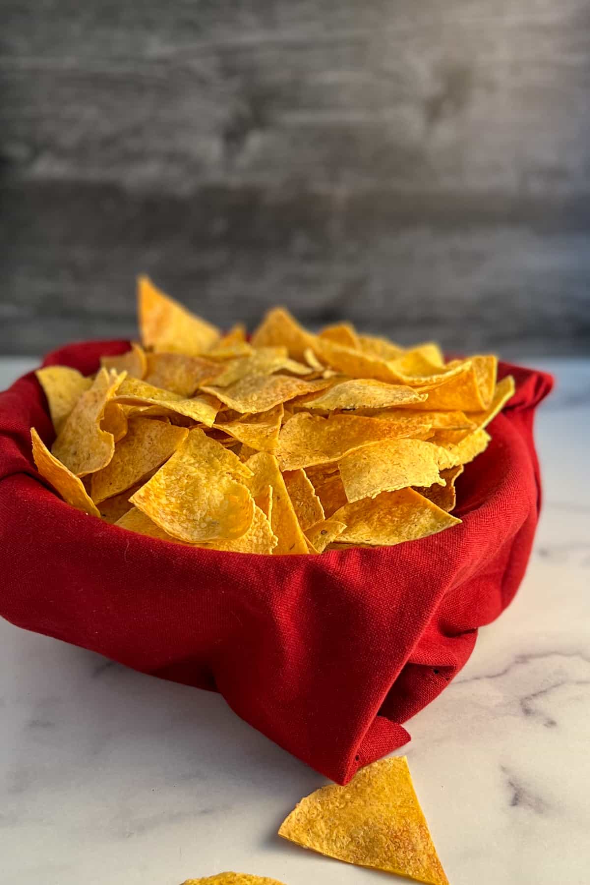 side view of oven baked tortilla chips in a bowl lined with a red napkin