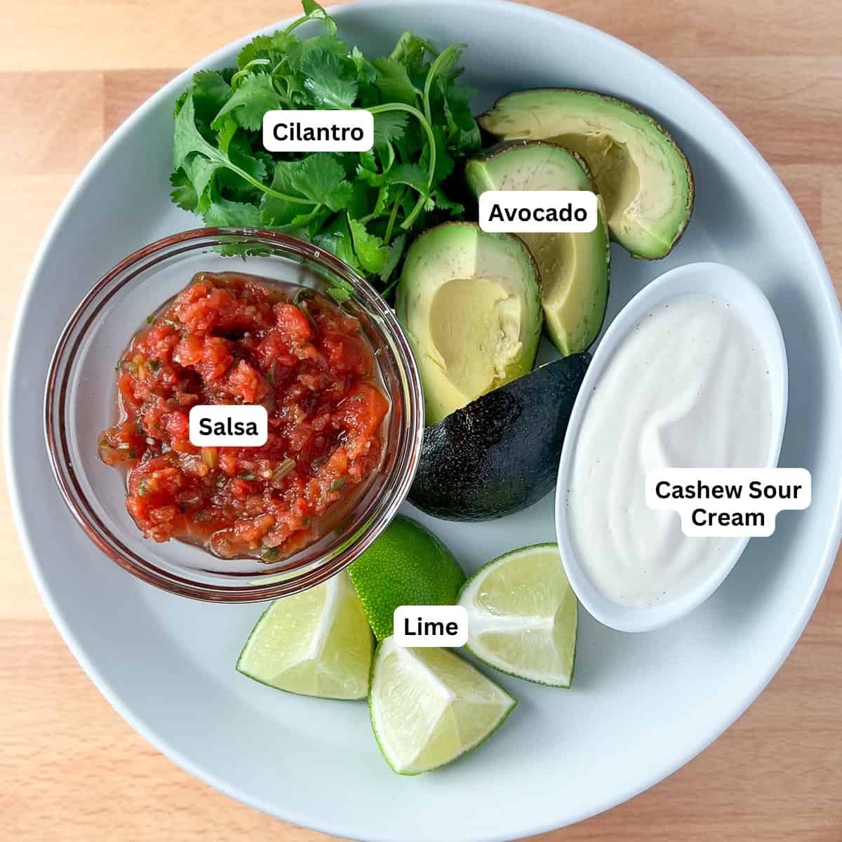 Vegan fajita toppings: salsa, fresh cilantro, sliced avocado, cashew cream and fresh lime wedges.