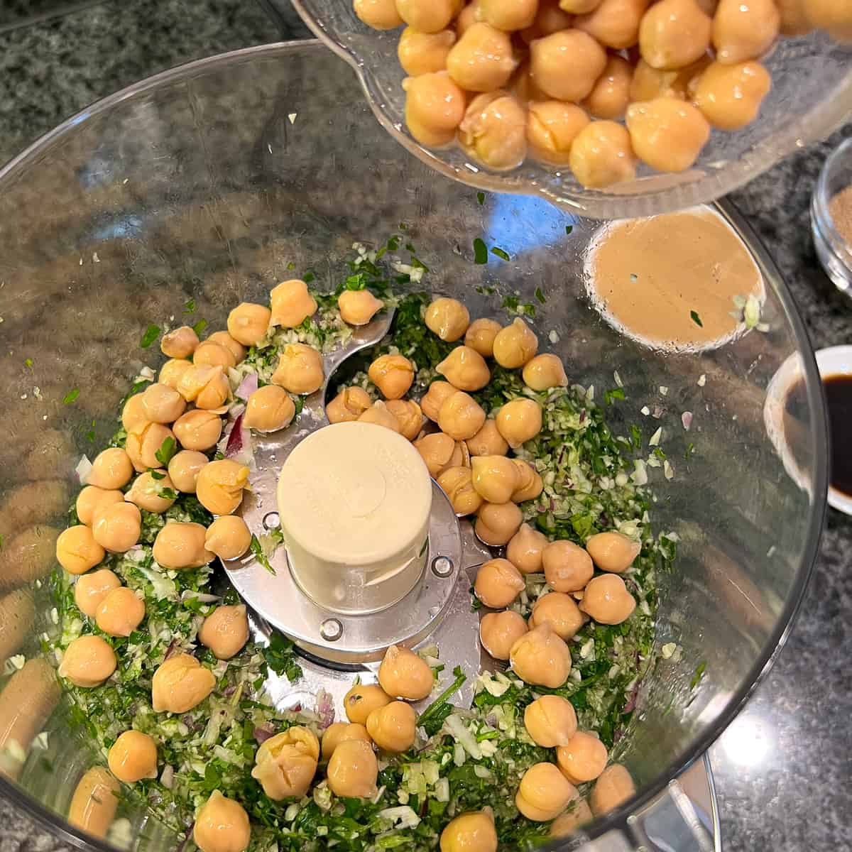 Chickpeas being added to food processor.