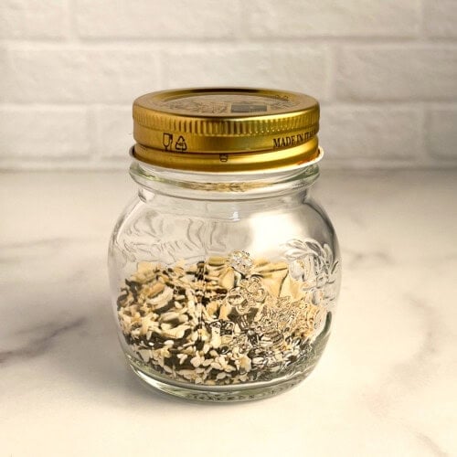 side view close up of everything bagel seasoning in a glass jar with gold lid
