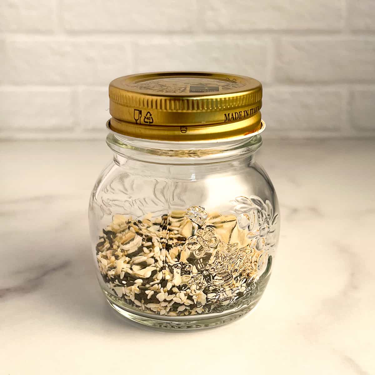 side view close up of a jar of everything bagel seasoning with gold lid