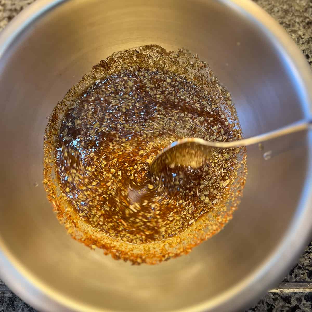 top view of fajita marinade in a mixing bowl with spoon stirring spices with liquid