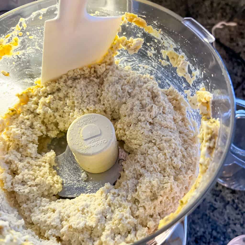 Tofu ricotta partially processed with a spatula scraping down the sides.