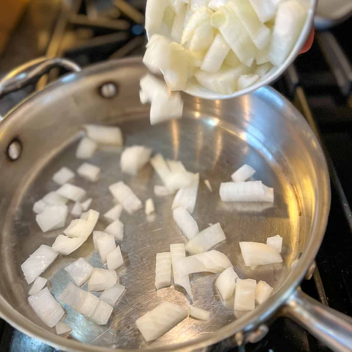 chopped onions being added to a hot pan
