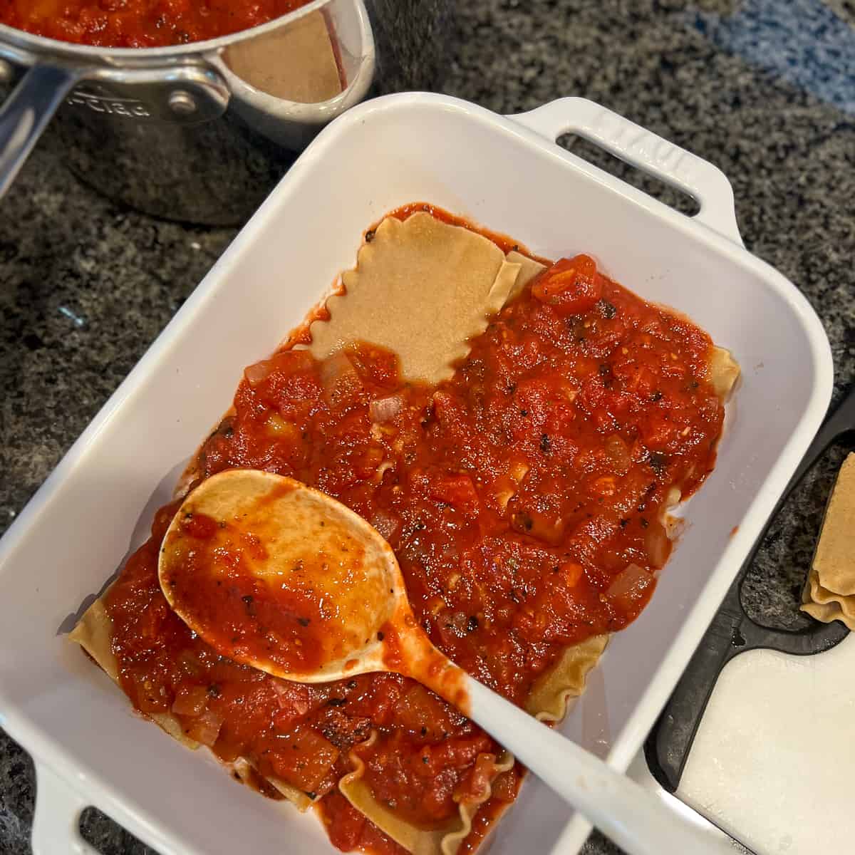 top view of lasagna being assembled with layer of pasta and sauce in a rectangular baking dish