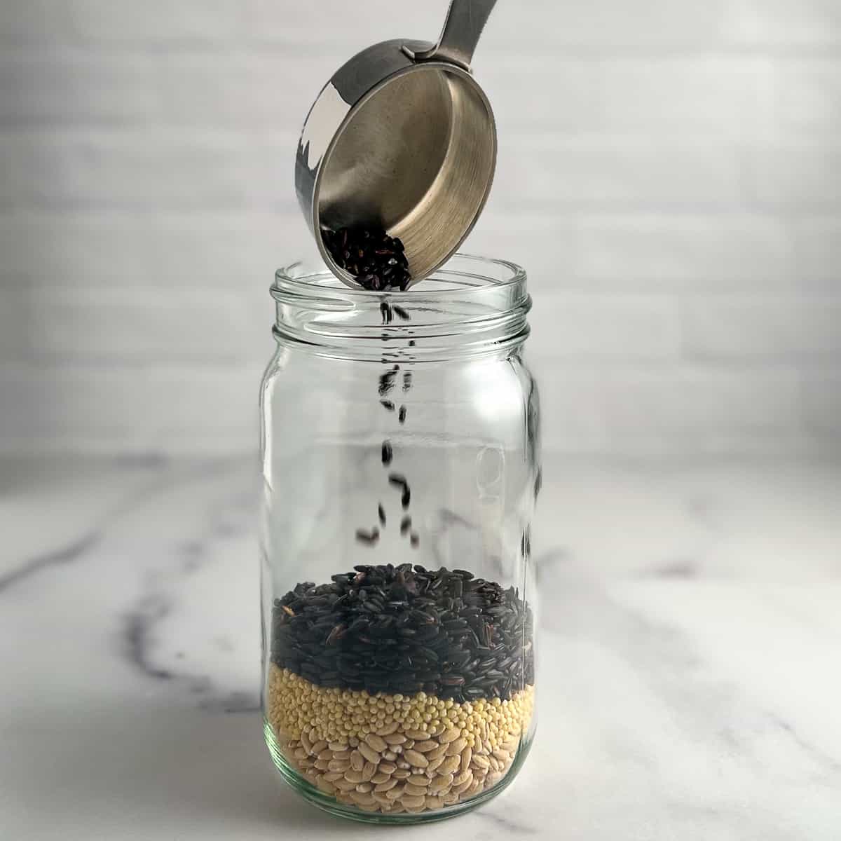 side view of ancient grains being poured into a mason jar