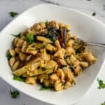 top side view close up of mushroom pasta in a white bowl with fresh parsley on top