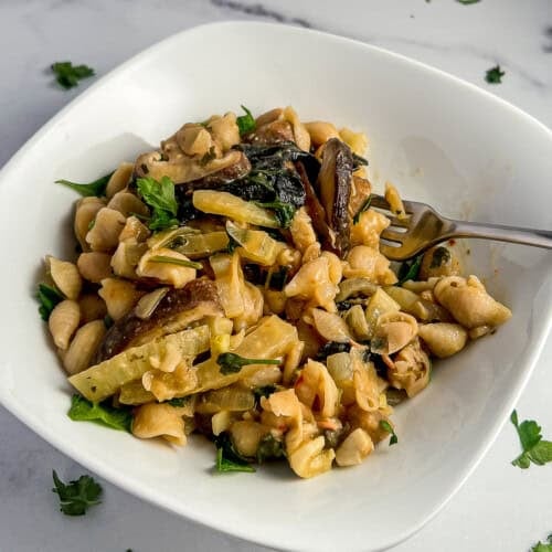 top side view close up of mushroom pasta in a white bowl with fresh parsley on top