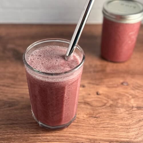 top side view close up of a pink pineapple weight loss smoothie with metal straw; and second smoothie in a mason jar blurred in the background