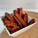 side top view close up of a square white bowl with cooked tempeh bacon leaning or standing up