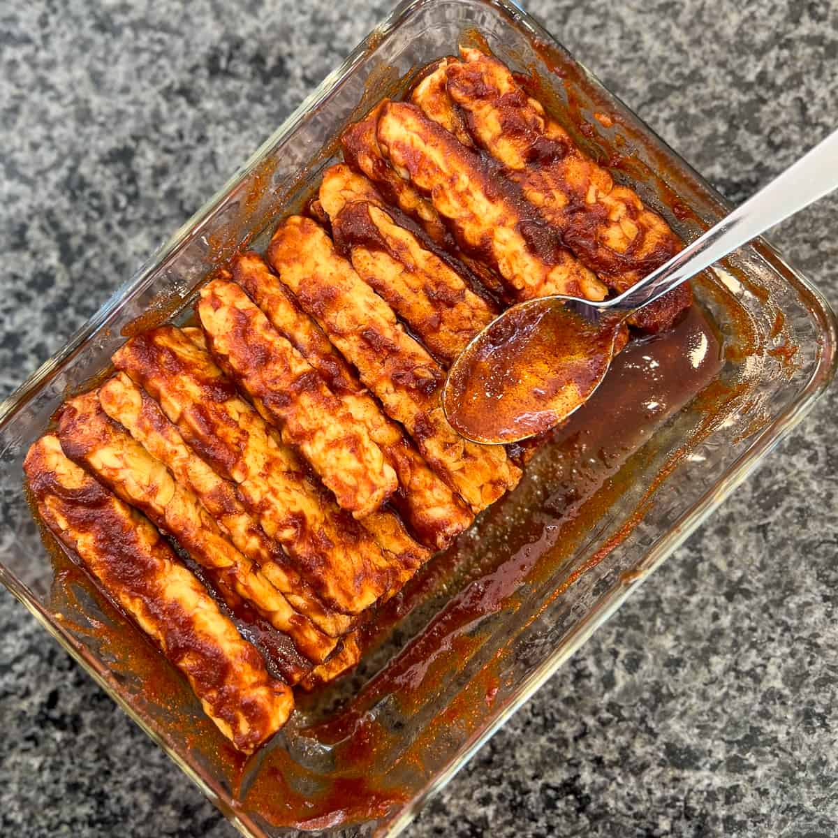 top view of tempeh bacon coated in sauce mixture