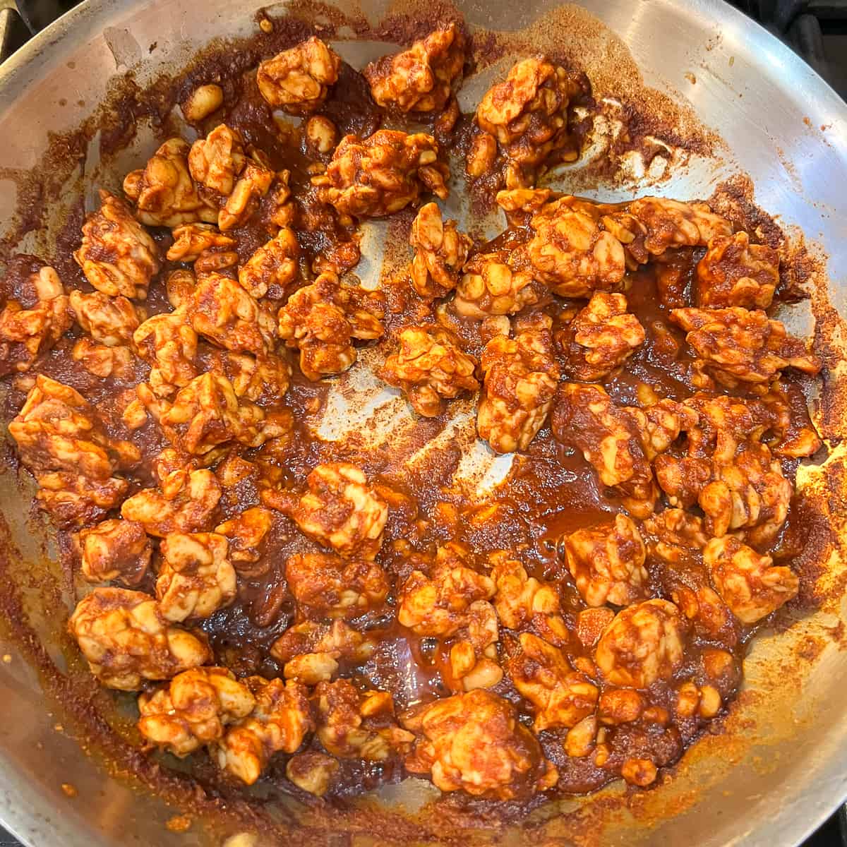 top view close up of cooked tempeh chorizo crumbles in a skillet with reduced red sauce