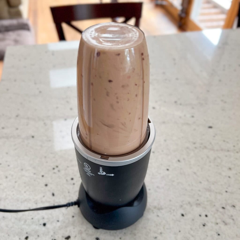 Peach banana smoothie being blended in a blender.