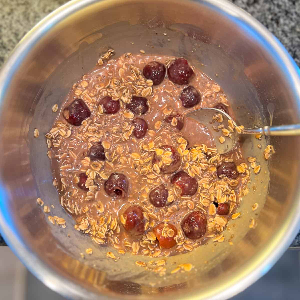 top view of oat mixture with cherries and a spoon on the side