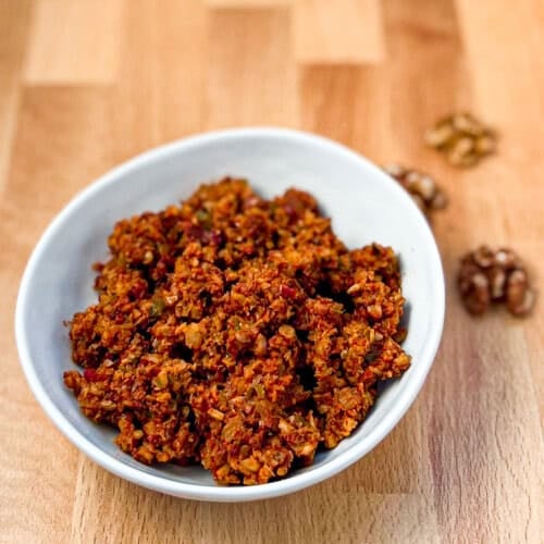 top side view close up of vegan walnut taco meat in a white bowl with loose walnuts on the side