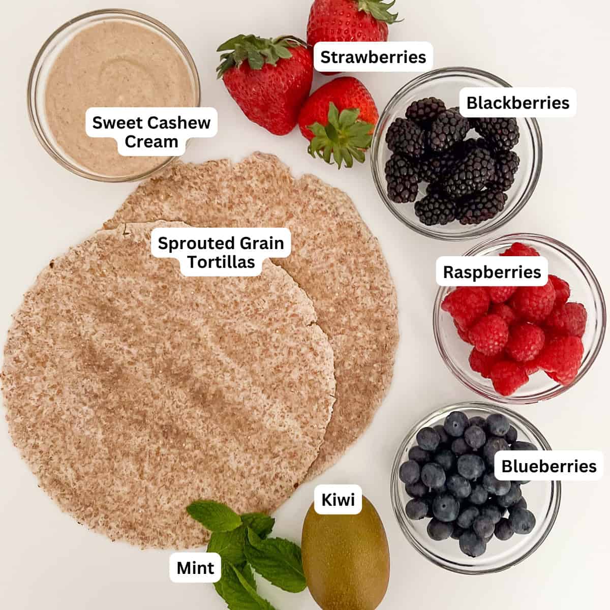 Ingredients for healthy fruit pizza: sweet cashew cream sauce, fresh berries, kiwi, mint and sprouted grain tortillas.