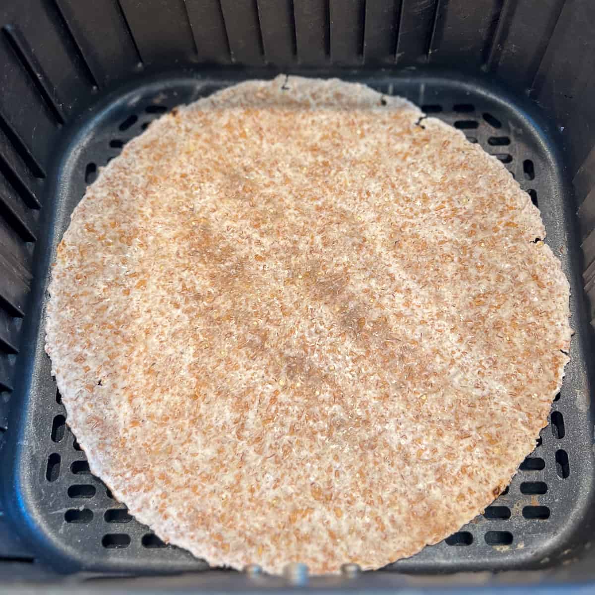 top view of whole grain tortilla in air fryer basket