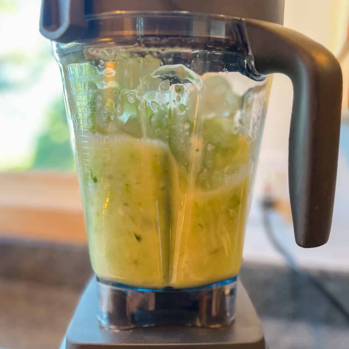 side view of celery smoothie being blended in a high speed blender
