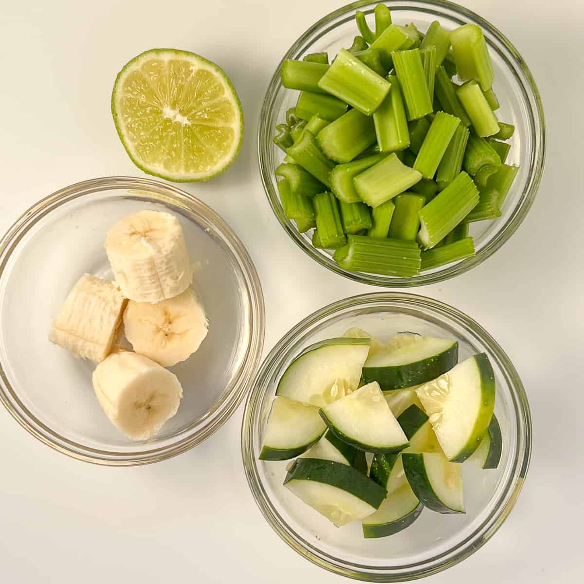 top view of some of the ingredients for smoothie: celery, cucumber, banana, lime