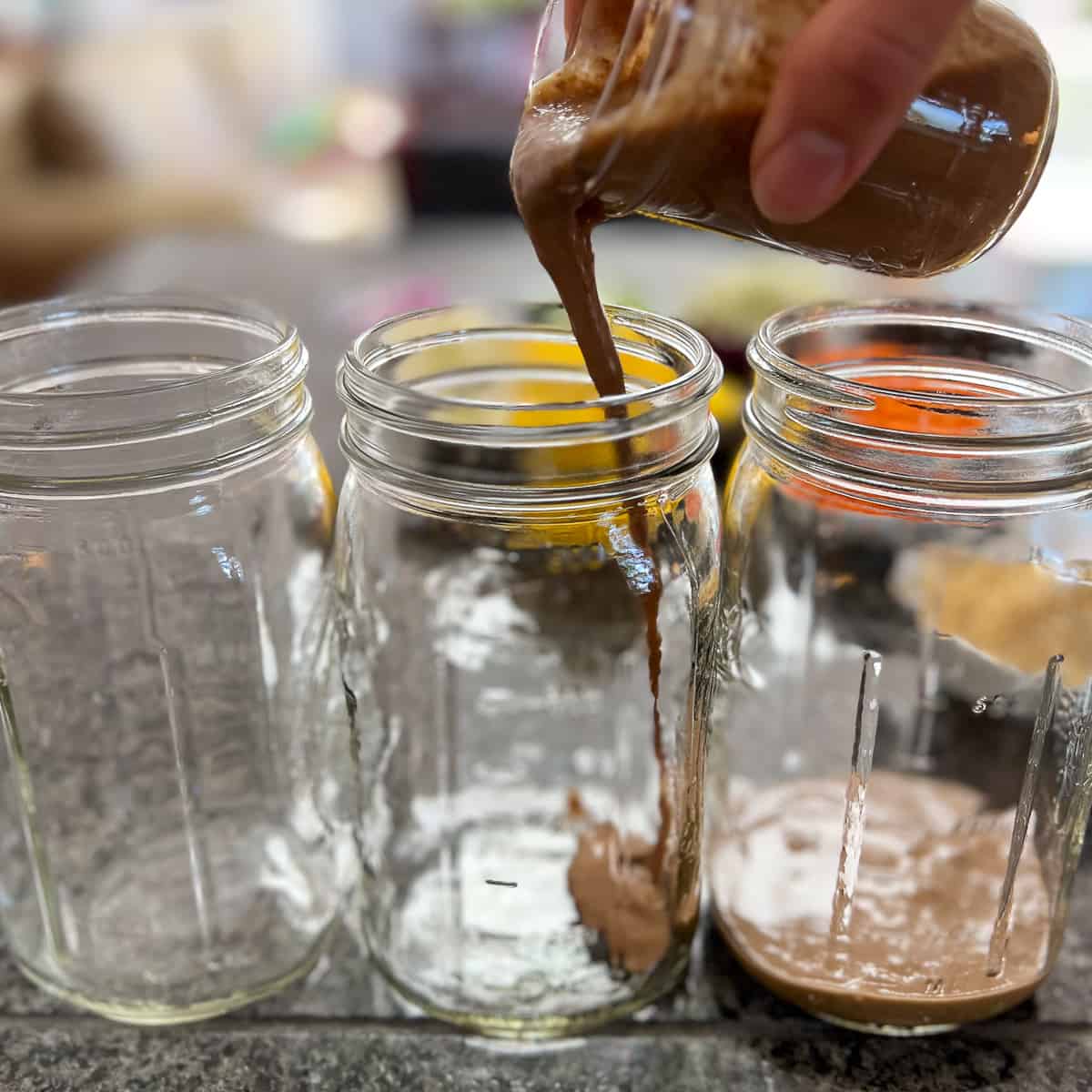 dressing being poured into mason jars