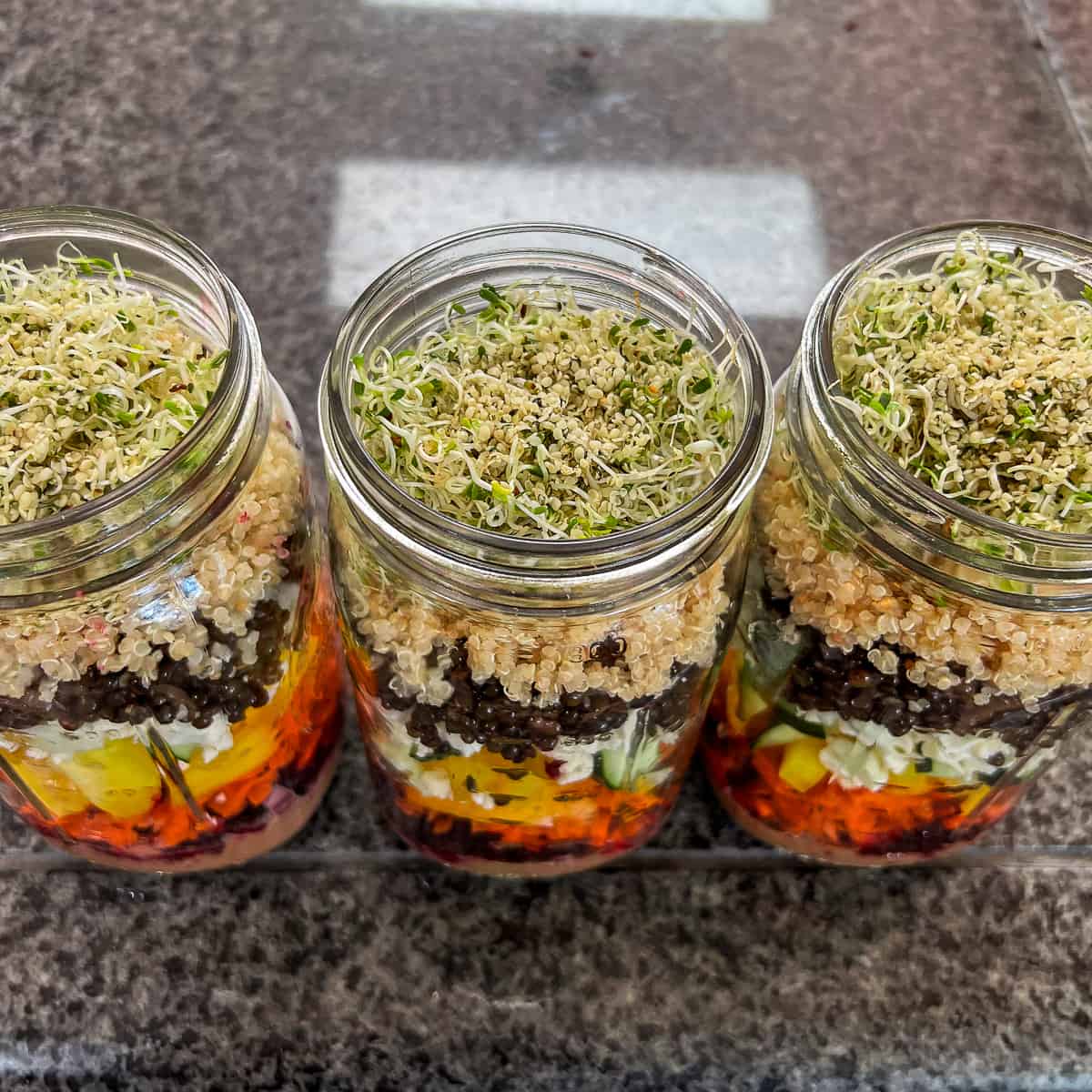 top side view close up of 3 mason jars with superfood salad ingredients lined up on countertop