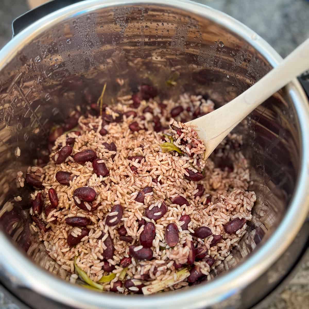 top view of rice and beans in an instant pot with wooden spoon stirring