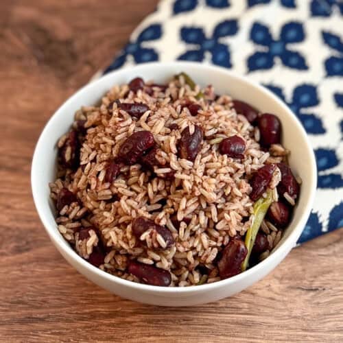 top side view close up of Jamaican rice and peas in a white bowl with blue print napkin blurred in the background