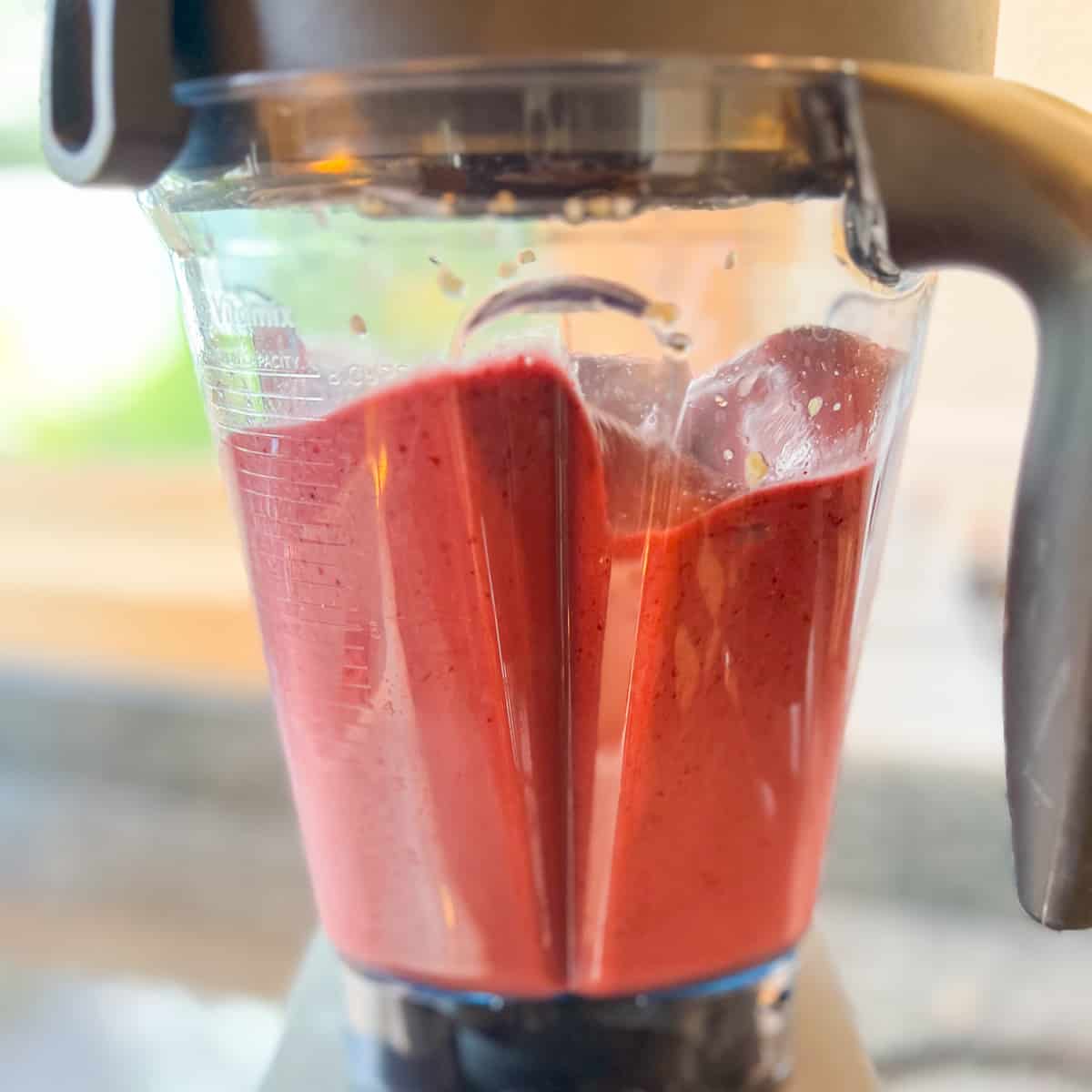 side view of mixed berry smoothie being blended in a high speed blender