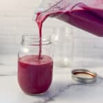 side view of mixed berry smoothie being poured into a mason jar
