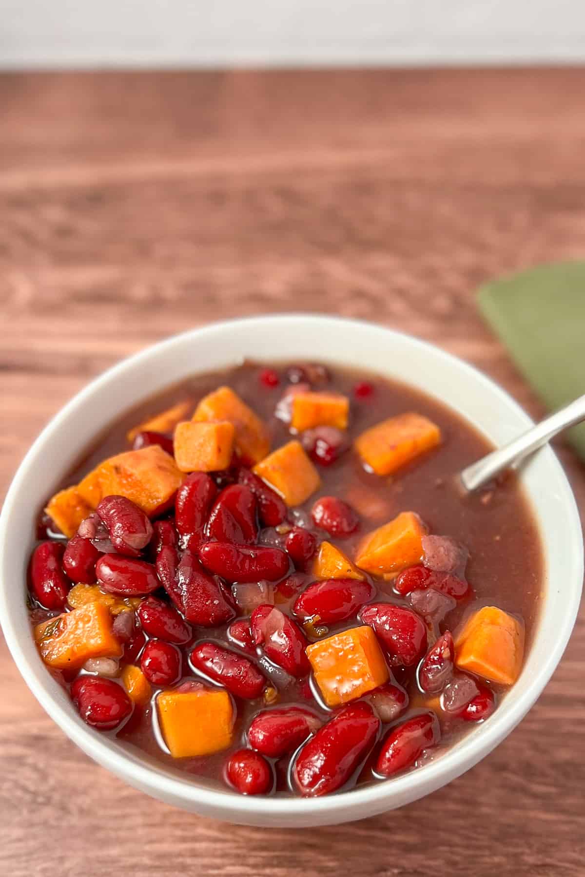 top side view of red kidney bean soup in a white bowl with spoon