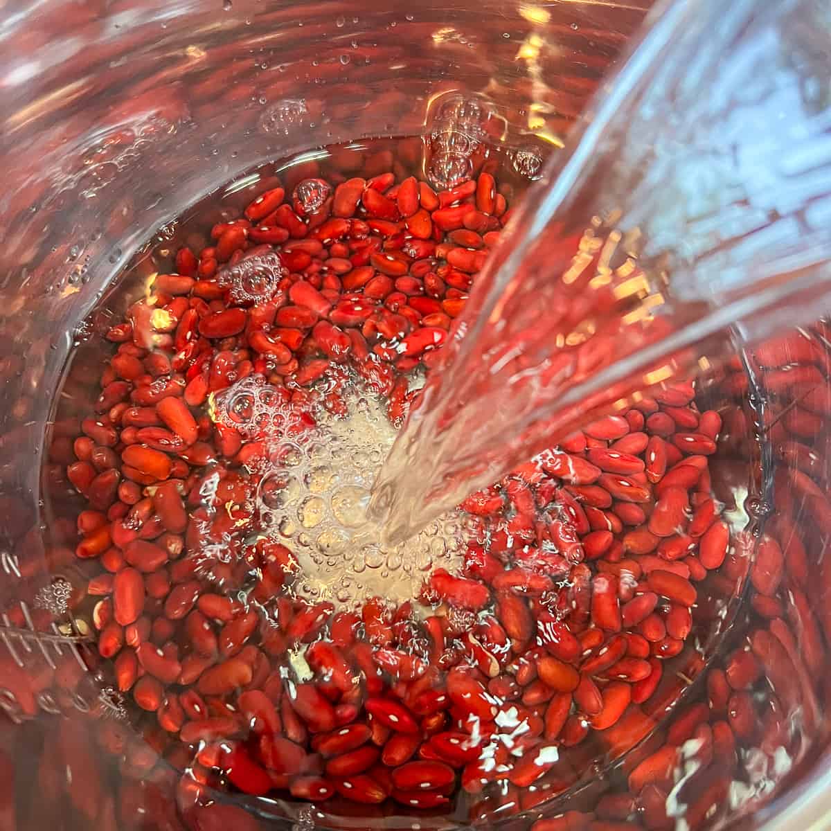top view close up of red kidney beans in the Instant Pot with water being poured in