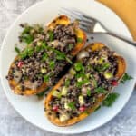 top view close up of two stuffed delicata squash halves on a plate with fork on the side