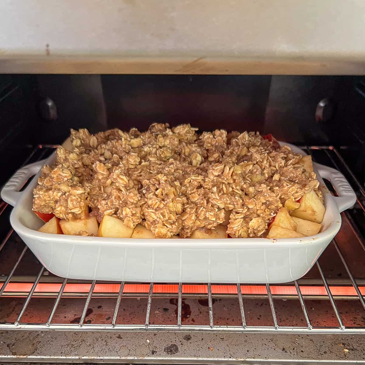 side view of apple crisp going into the oven to bake
