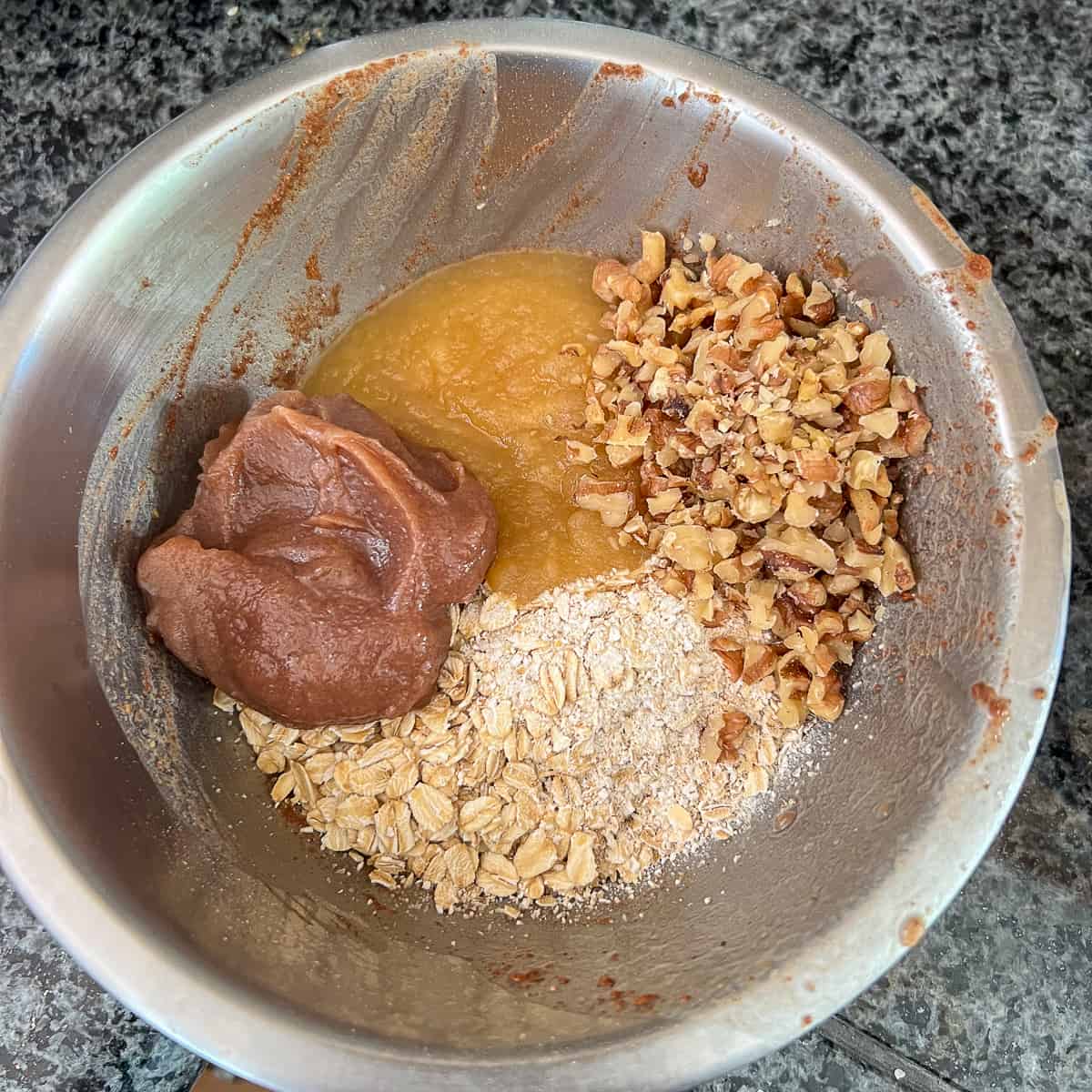 top view of a mixing bowl with date syrup, oats, walnuts and apple sauce