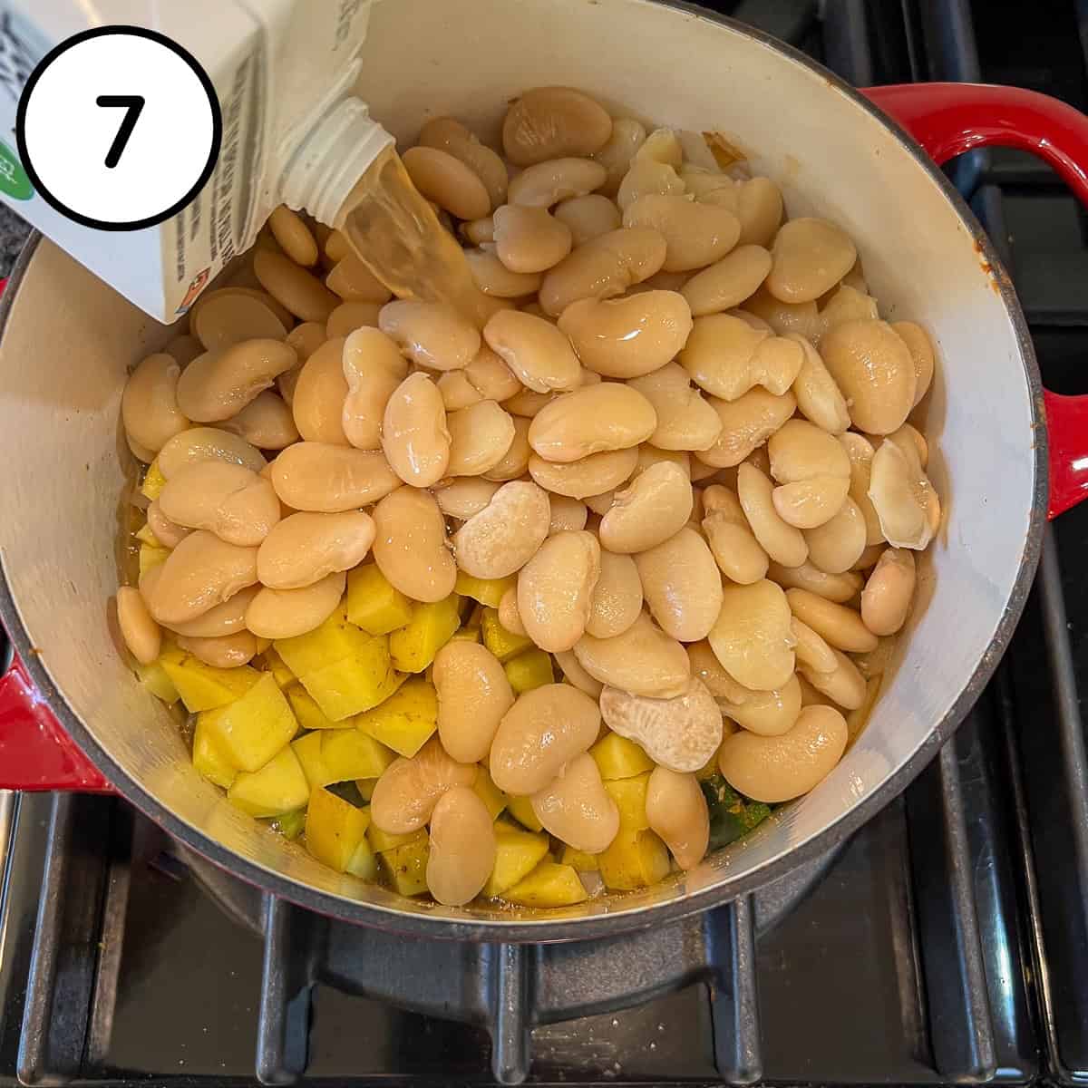 Vegetable broth being added to the pot with beans and veggies.
