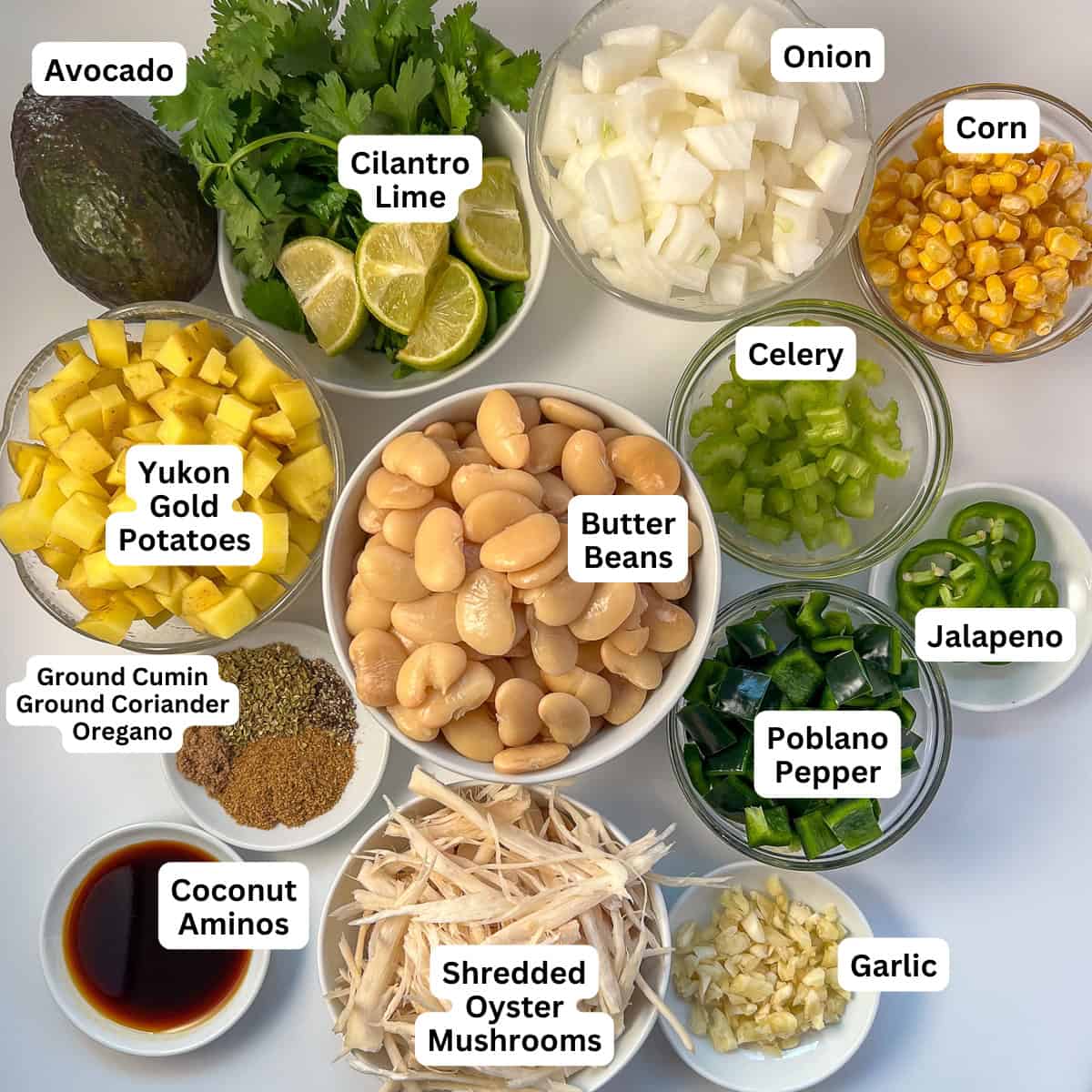 The ingredients for vegan white bean chili: butter beans, shredded oyster mushrooms, diced potatoes, chopped onion, corn, chopped celery, chopped peppers, minced garlic and herbs and spices.