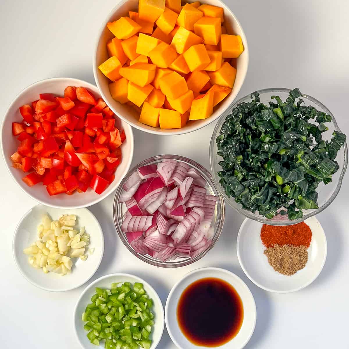 ingredients for butternut squash breakfast hash: cubed butternut squash, chopped onion, bell pepper, kale and other spices