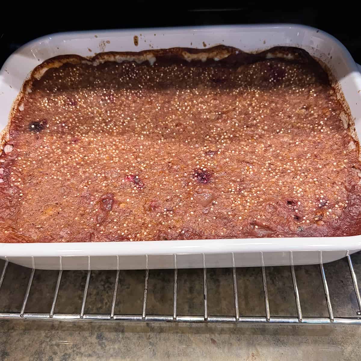 A casserole dish with cherry quinoa breakfast bake coming out of the oven.