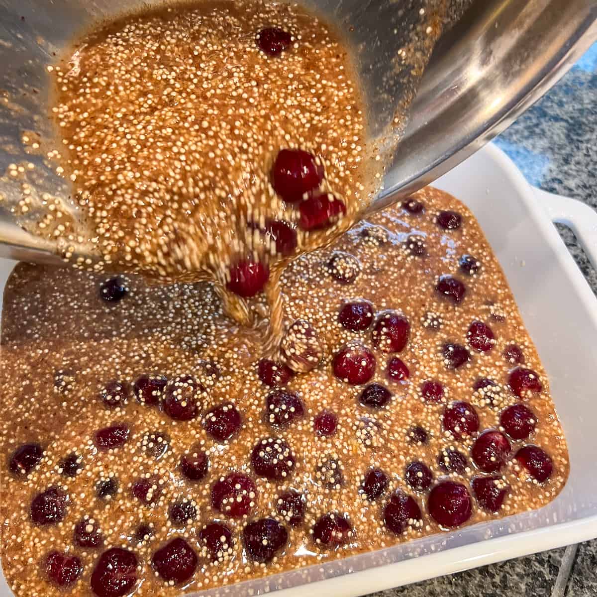 The cherry quinoa mixture being poured into a casserole dish.