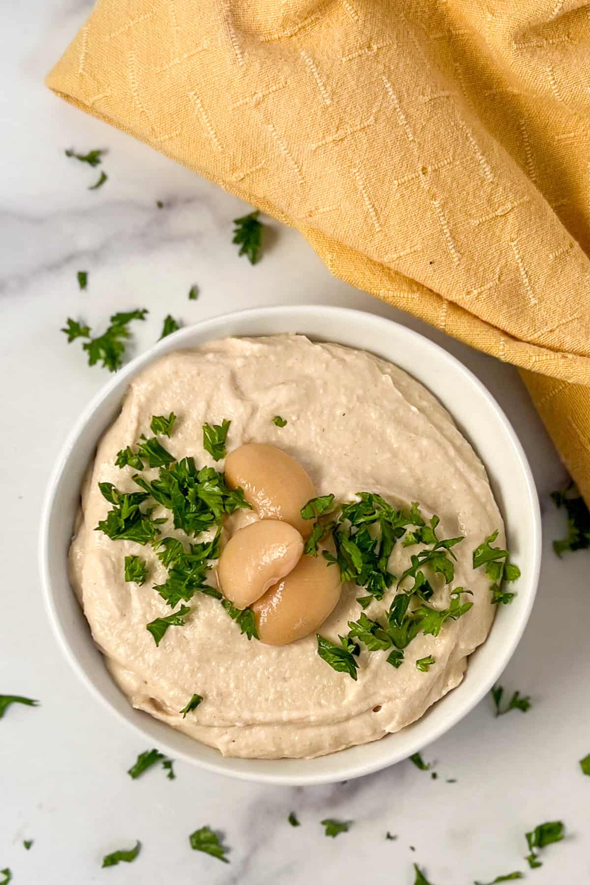 A bowl of butter bean hummus with fresh chopped parsley on top.