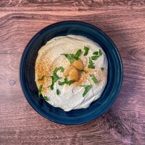 Butter bean hummus in a bowl topped with fresh chopped cilantro and a dusting of cayenne pepper.