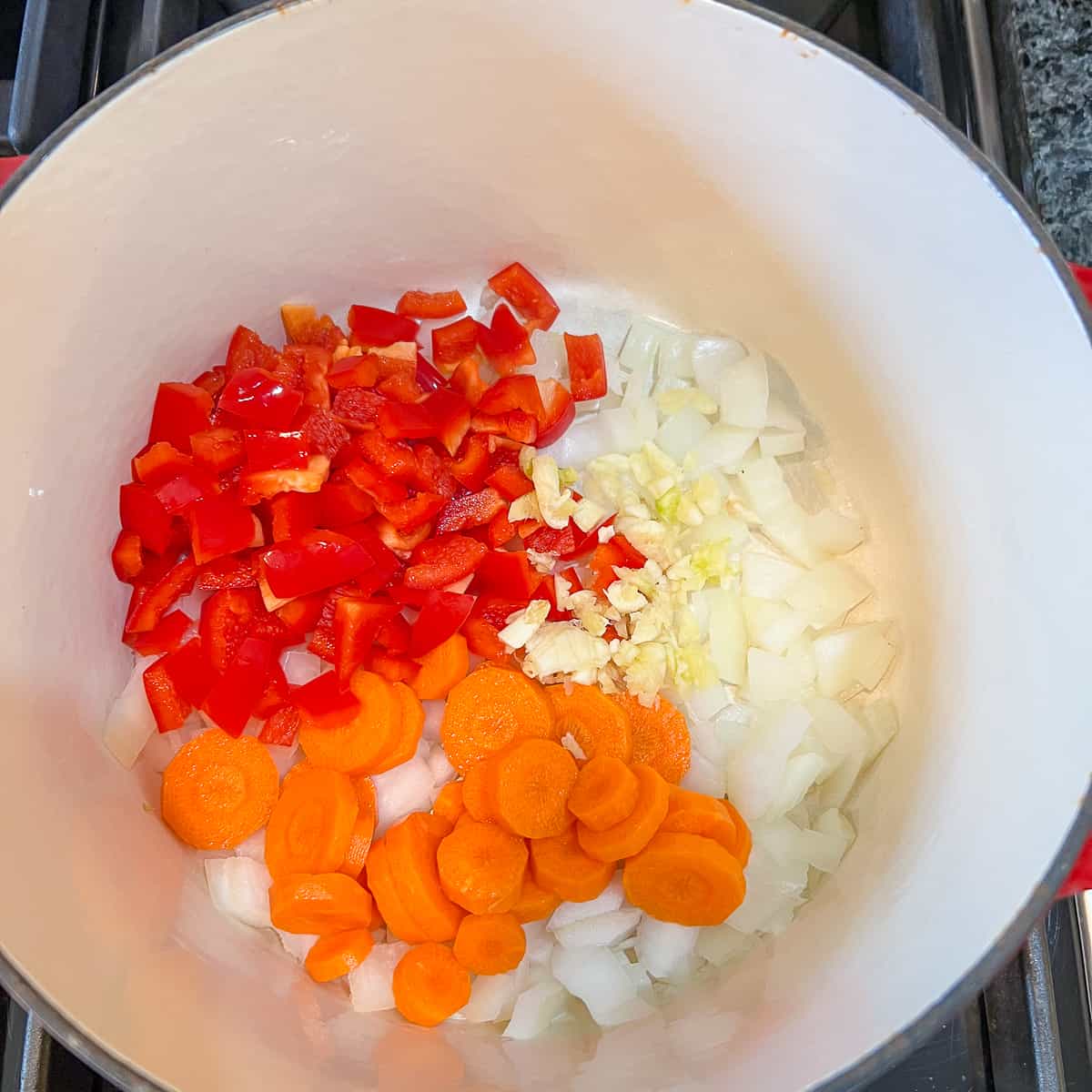 A pot with chopped vegetables on the stovetop.