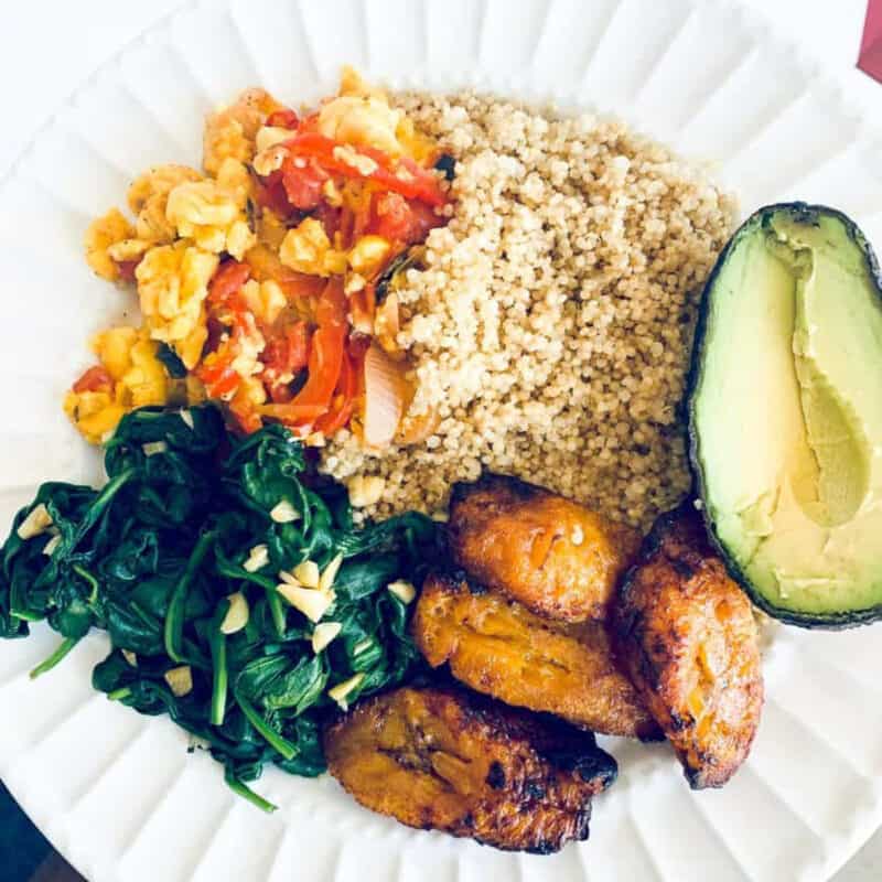 Vegan ackee dinner with ackee, quinoa, plantains, spinach and avocado on a plate.