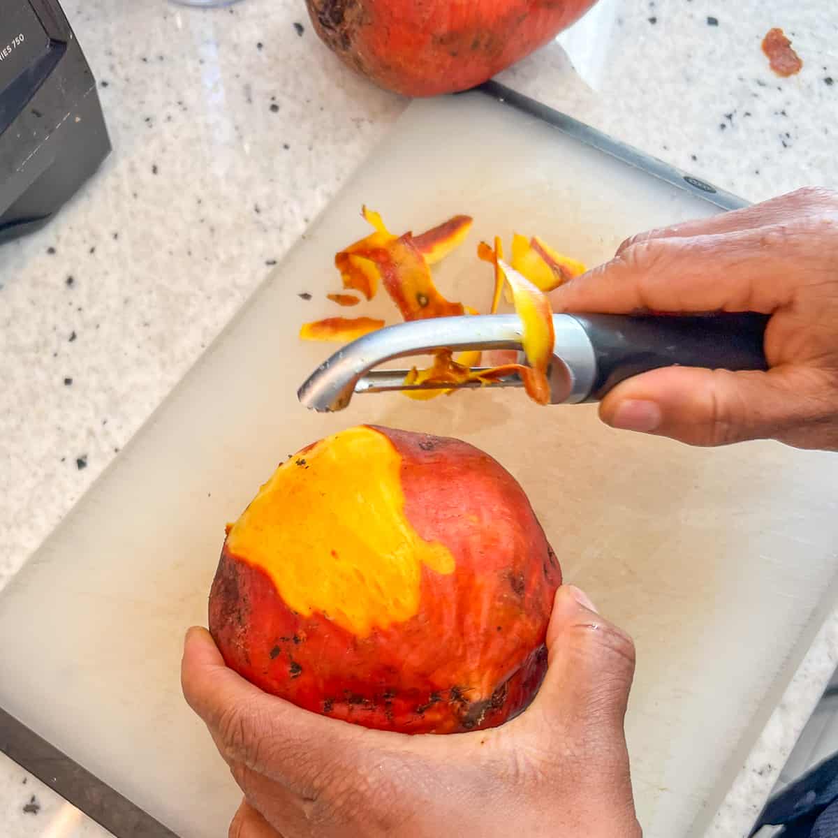 A woman's hand holding a golden beet in one hand and a peeler in the other removing rough spots.