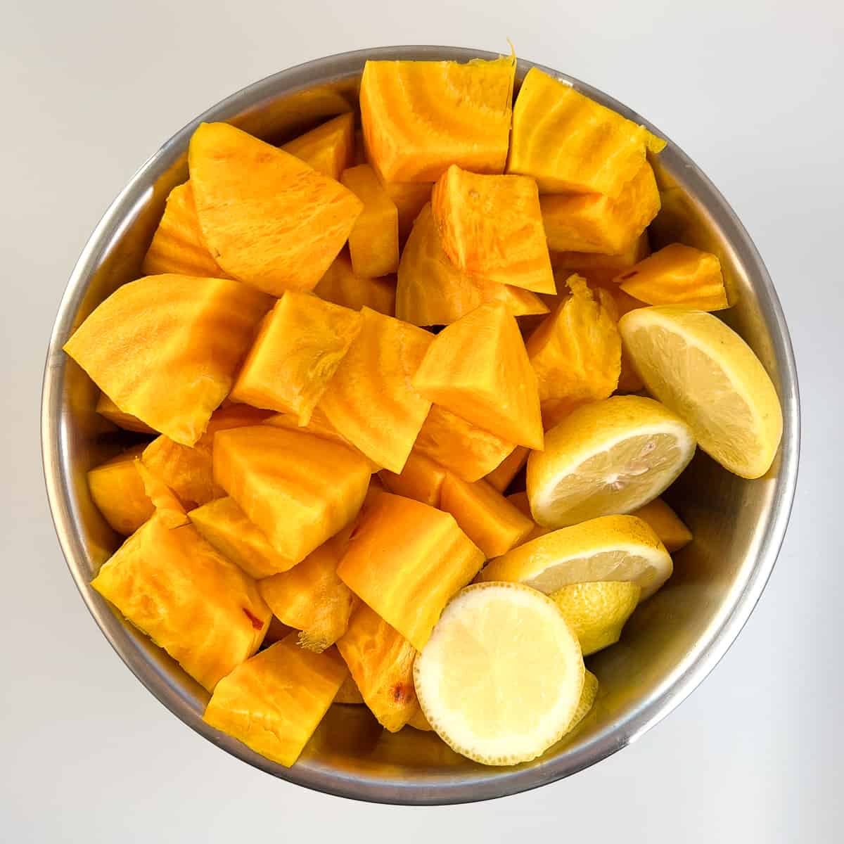 A bowl with chunks of golden beets and lemon slices, ready for juicing.