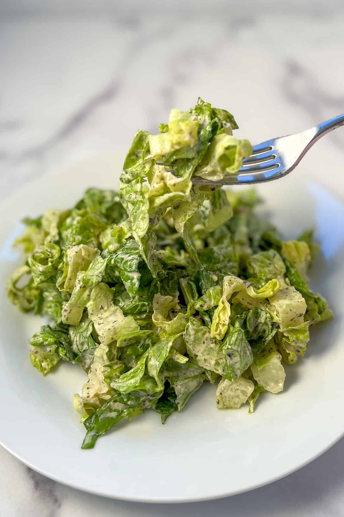 Vegan caesar salad on a plate with fork dishing up a bite.