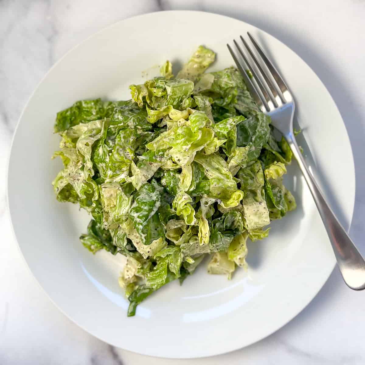 Vegan Caesar salad on a plate with fork on the side.