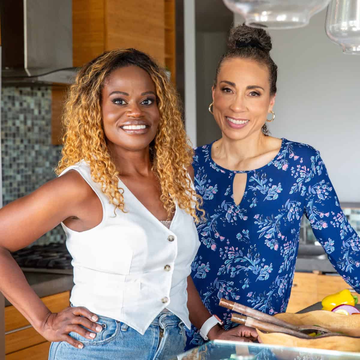Two women standing in a kitchen smiling.