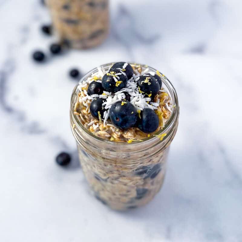 Lemon blueberry overnight oats in a mason jar topped with coconut flakes.